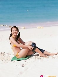 Energetic asian beauty playing on the beach in her bikini